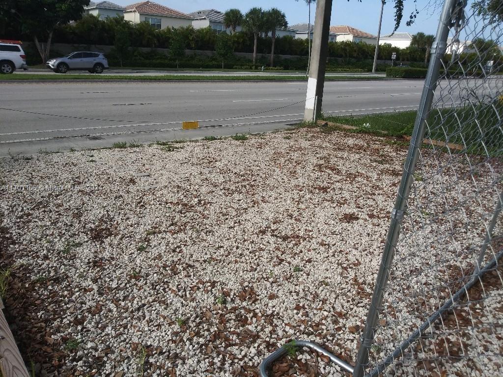 A gravel-covered lot is enclosed by a chain-link fence next to a paved road — Pembroke Rd, West Park FL 33023, WEST PARK, FL