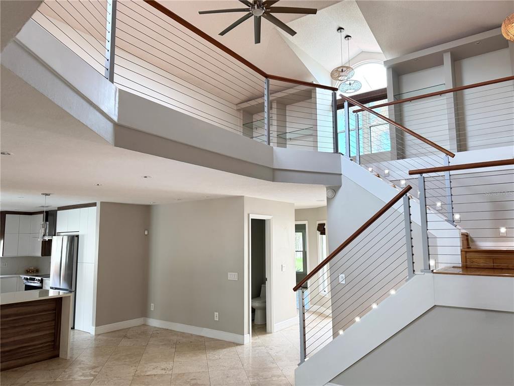 A modern interior features a two-story foyer with a cable-railing staircase and tiled flooring — 8214 ROLLA COURT, ORLANDO, FL