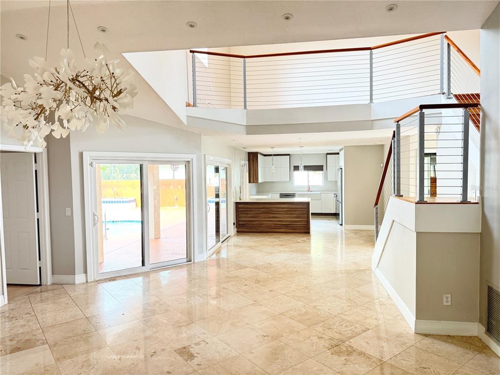 A bright, open-concept living area features tile flooring, a modern chandelier, and a staircase — 8214 ROLLA COURT, ORLANDO, FL