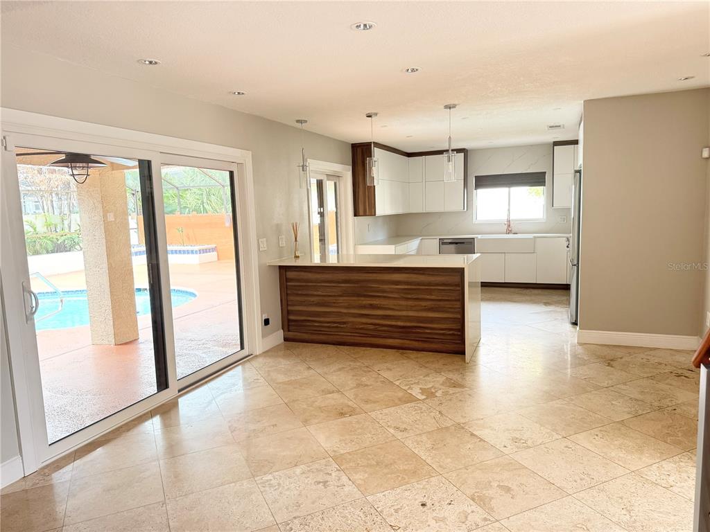 A kitchen with a wood-paneled island and white cabinets overlooks a pool through sliding doors — 8214 ROLLA COURT, ORLANDO, FL