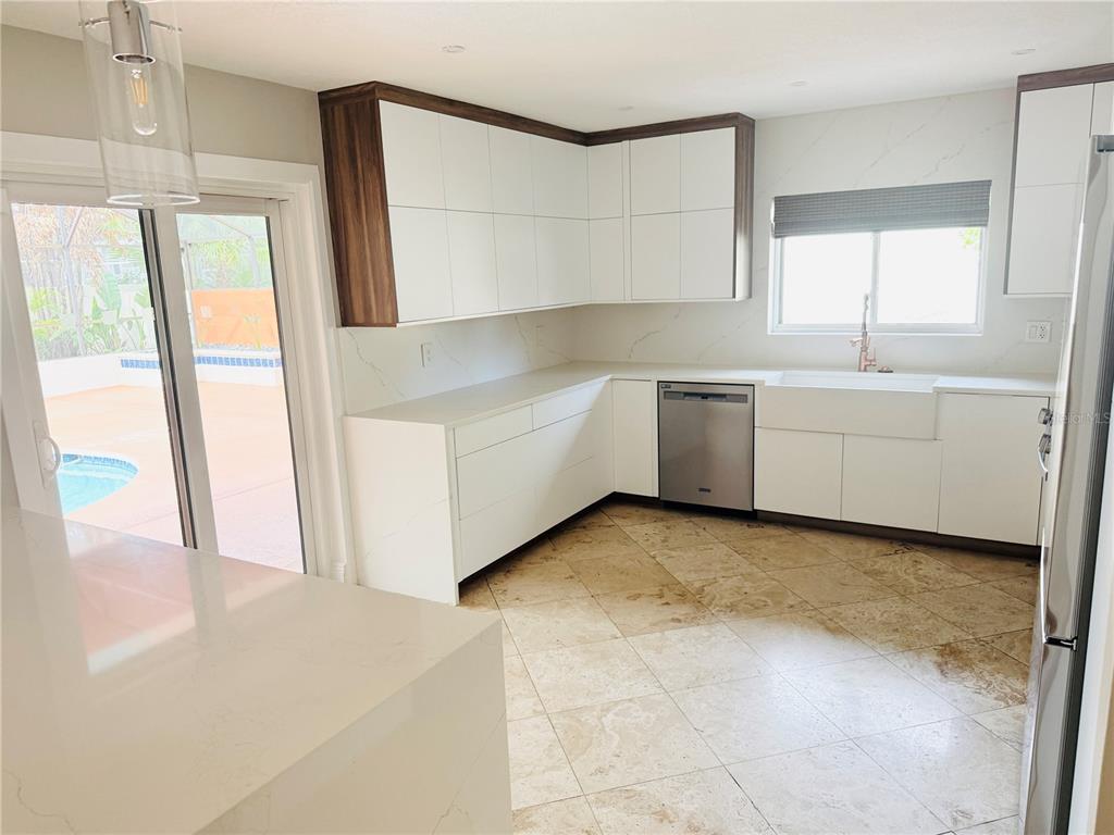 A modern kitchen features white flat-panel cabinetry, marble-look countertops, stainless steel appliances, and tile flooring — 8214 ROLLA COURT, ORLANDO, FL
