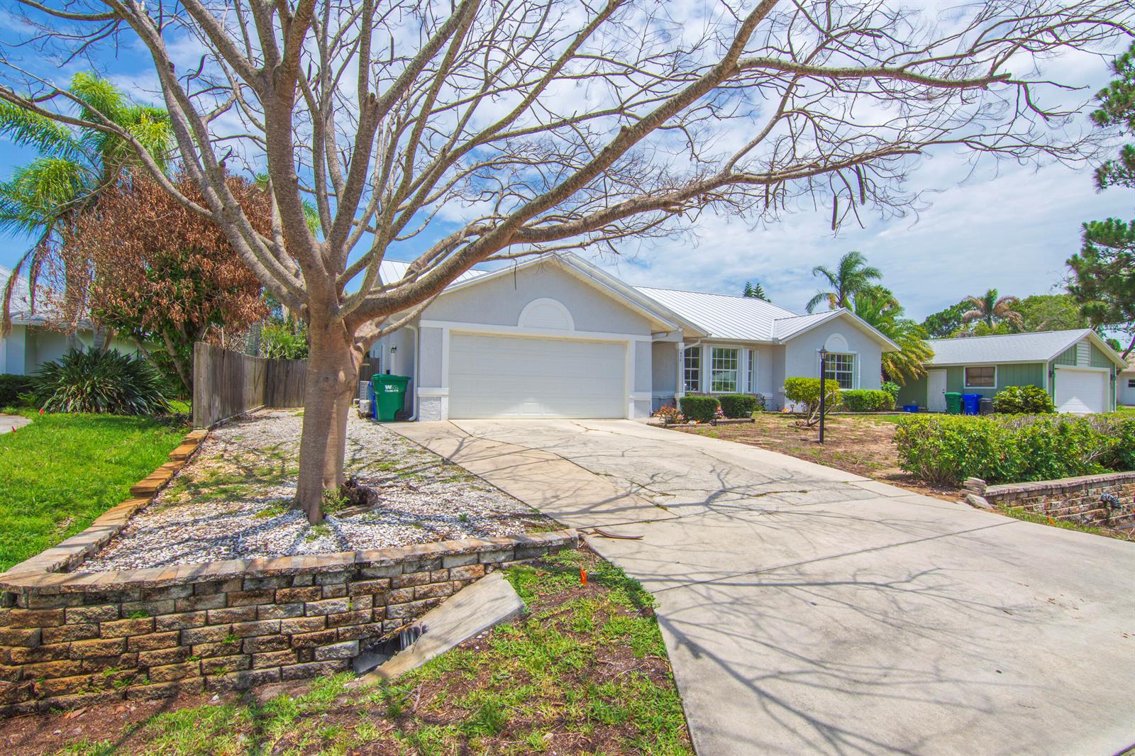 A single-story house with a white garage, metal roof, and a stone retaining wall — 474 Arbor Street, Sebastian FL 32958, SEBASTIAN, FL