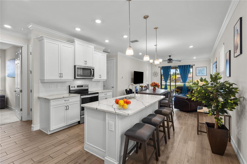 A kitchen with white cabinets, a marble-topped island, and wood-look tile flooring — 229 TERAMO WAY, NOKOMIS, FL