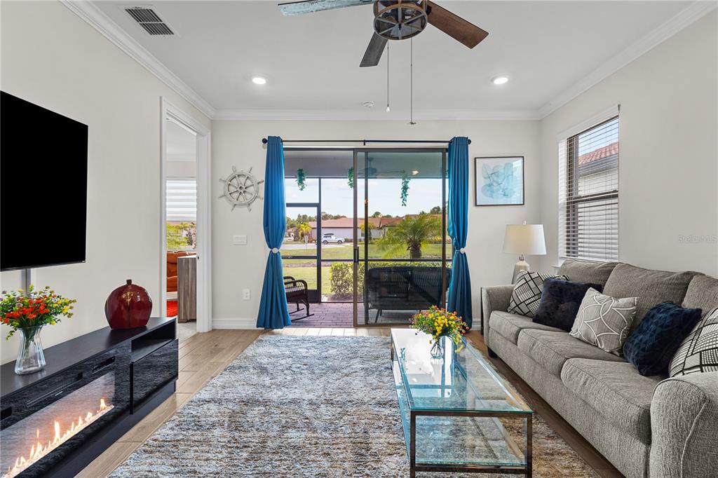 A living room features a fireplace, a glass coffee table, a sofa, and sliding glass doors — 229 TERAMO WAY, NOKOMIS, FL