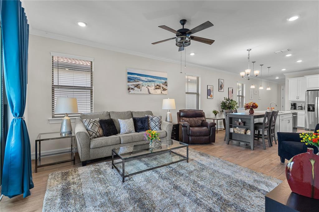 An open-concept living and dining area features a grey sofa, leather recliner, and kitchen island — 229 TERAMO WAY, NOKOMIS, FL