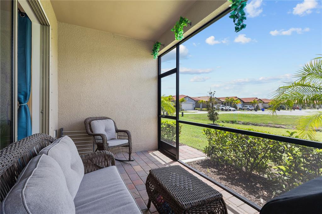 A screened-in patio features wicker furniture, a paver floor, and a view of the neighborhood — 229 TERAMO WAY, NOKOMIS, FL