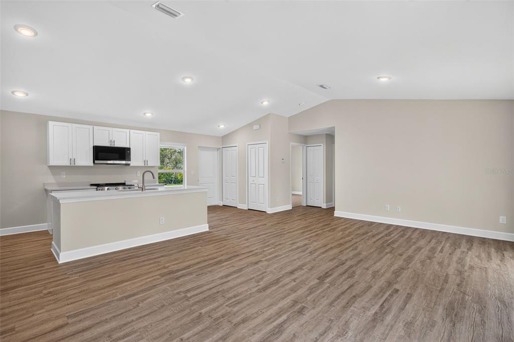 A kitchen with white cabinets and a breakfast bar opens into a spacious living area — 23477 BRANCH AVENUE, PORT CHARLOTTE, FL