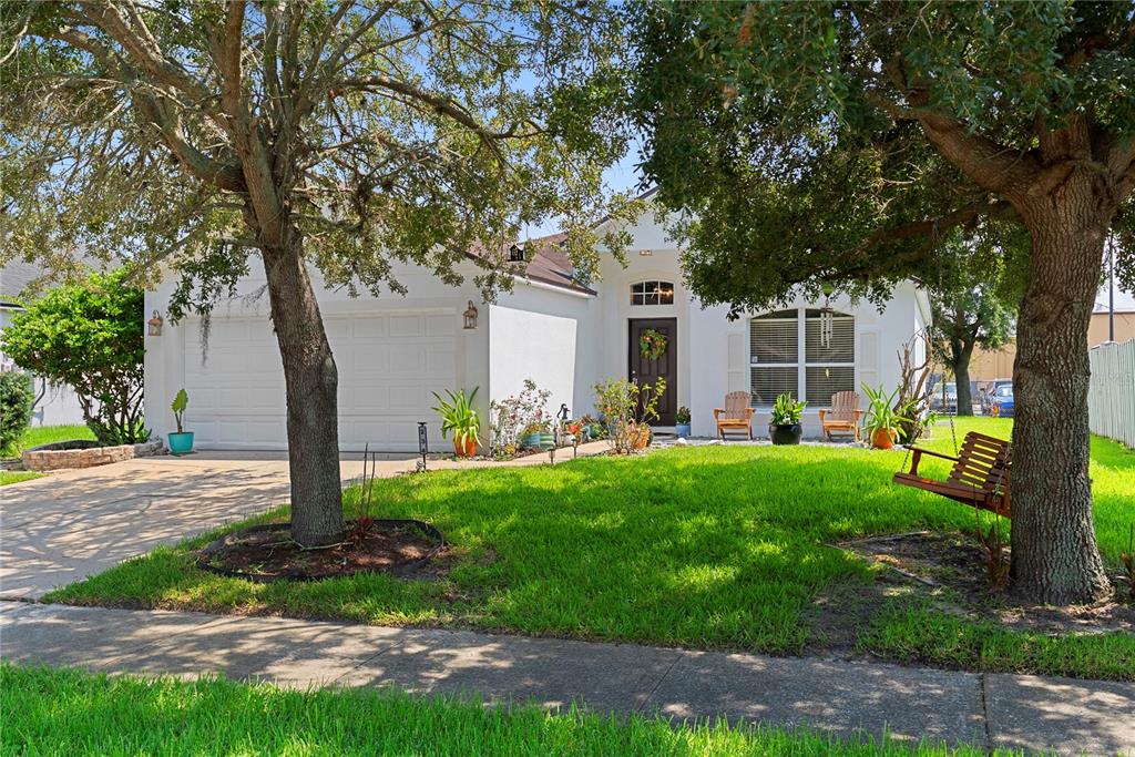 A white single-story house with a two-car garage, front lawn, and large shade trees — 234 GRAND ROYAL CIRCLE, WINTER GARDEN, FL