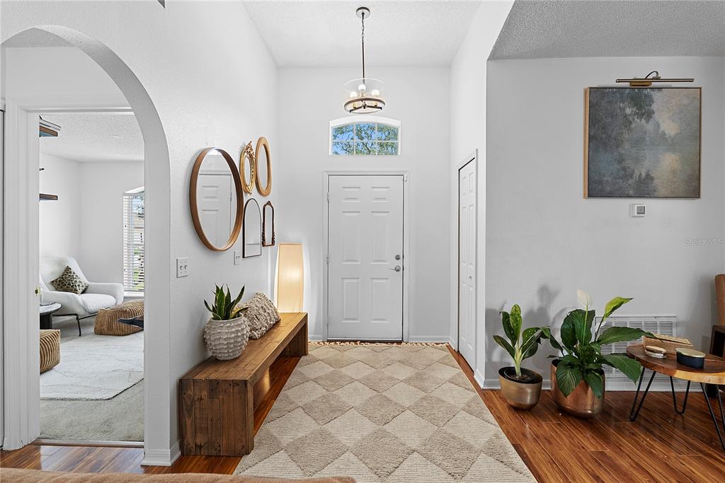 A bright entryway features a wooden bench, a patterned rug, and a front door — 234 GRAND ROYAL CIRCLE, WINTER GARDEN, FL