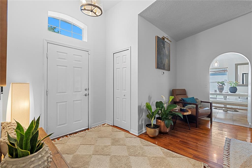 A bright entryway features a white front door, hardwood floors, and an arched doorway — 234 GRAND ROYAL CIRCLE, WINTER GARDEN, FL