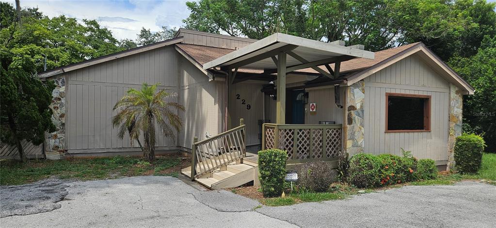 The exterior of a single-story building features wood siding, stone accents, and a covered porch — 229 AVENUE K SE, WINTER HAVEN, FL