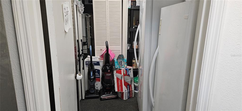 A narrow utility closet contains two upright vacuums, paper products, and a white freezer — 229 AVENUE K SE, WINTER HAVEN, FL