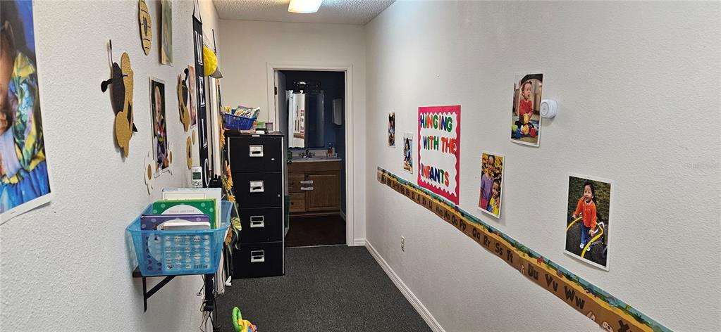 A hallway in a daycare facility features alphabet wall decor, children's photos, and a black cabinet — 229 AVENUE K SE, WINTER HAVEN, FL