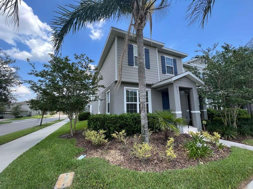 A two-story house with gray siding and blue shutters stands beside a street sign — 6131 ELFIN HERB WAY, WINTER GARDEN, FL