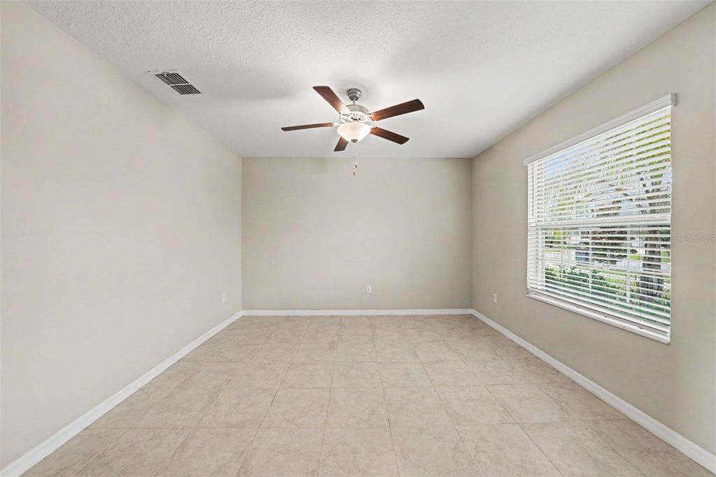 An empty room with beige walls, tile flooring, and a ceiling fan — 12961 WILDFLOWER MEADOW DR, RIVERVIEW, FL