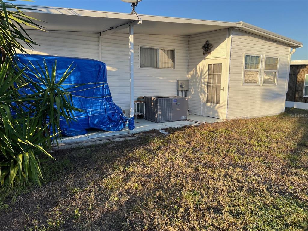 The exterior of a white mobile home features a covered patio, air conditioning unit, and lawn — 220 ROYAL PALM CIRCLE, LARGO, FL