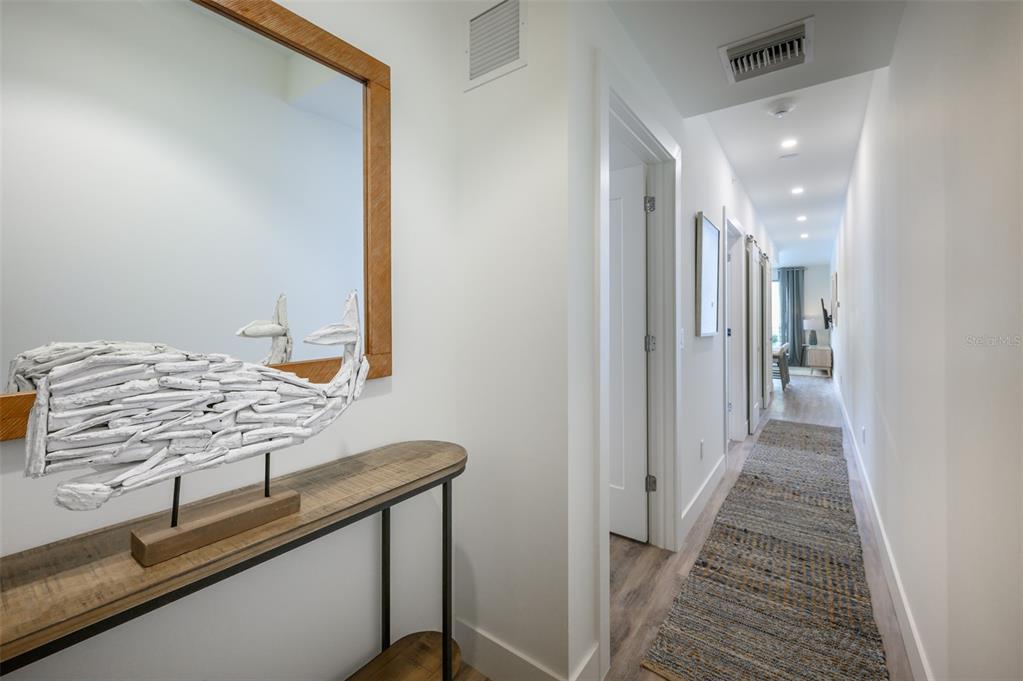 A hallway features a wooden console table with a driftwood whale sculpture and a runner rug — 1703 N TAMIAMI TRAIL UNIT 207, SARASOTA, FL