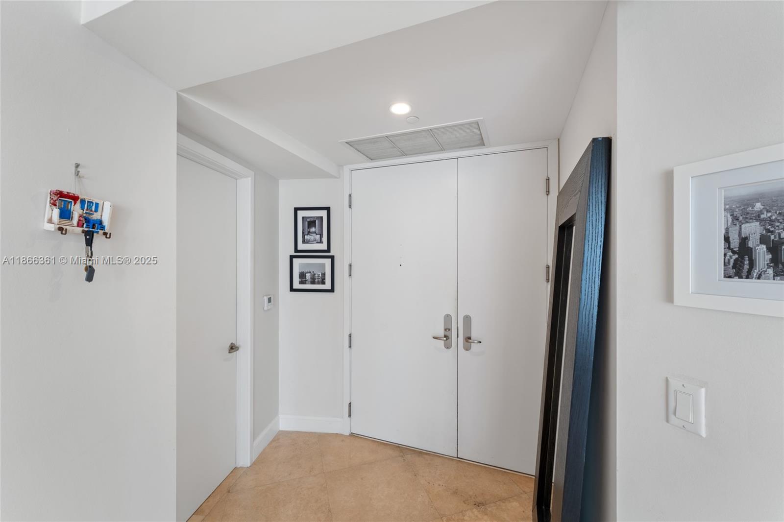 A white double-door entryway features tiled floors, a leaning mirror, and framed wall art — 901 Brickell Key Blvd # 2801, Miami FL 33131, MIAMI, FL