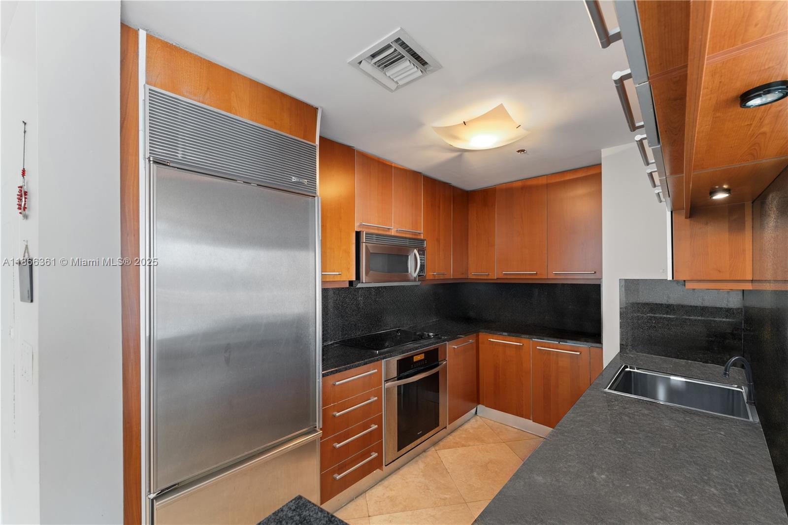 A kitchen features wood cabinets, stainless steel appliances, and dark granite countertops — 901 Brickell Key Blvd # 2801, Miami FL 33131, MIAMI, FL