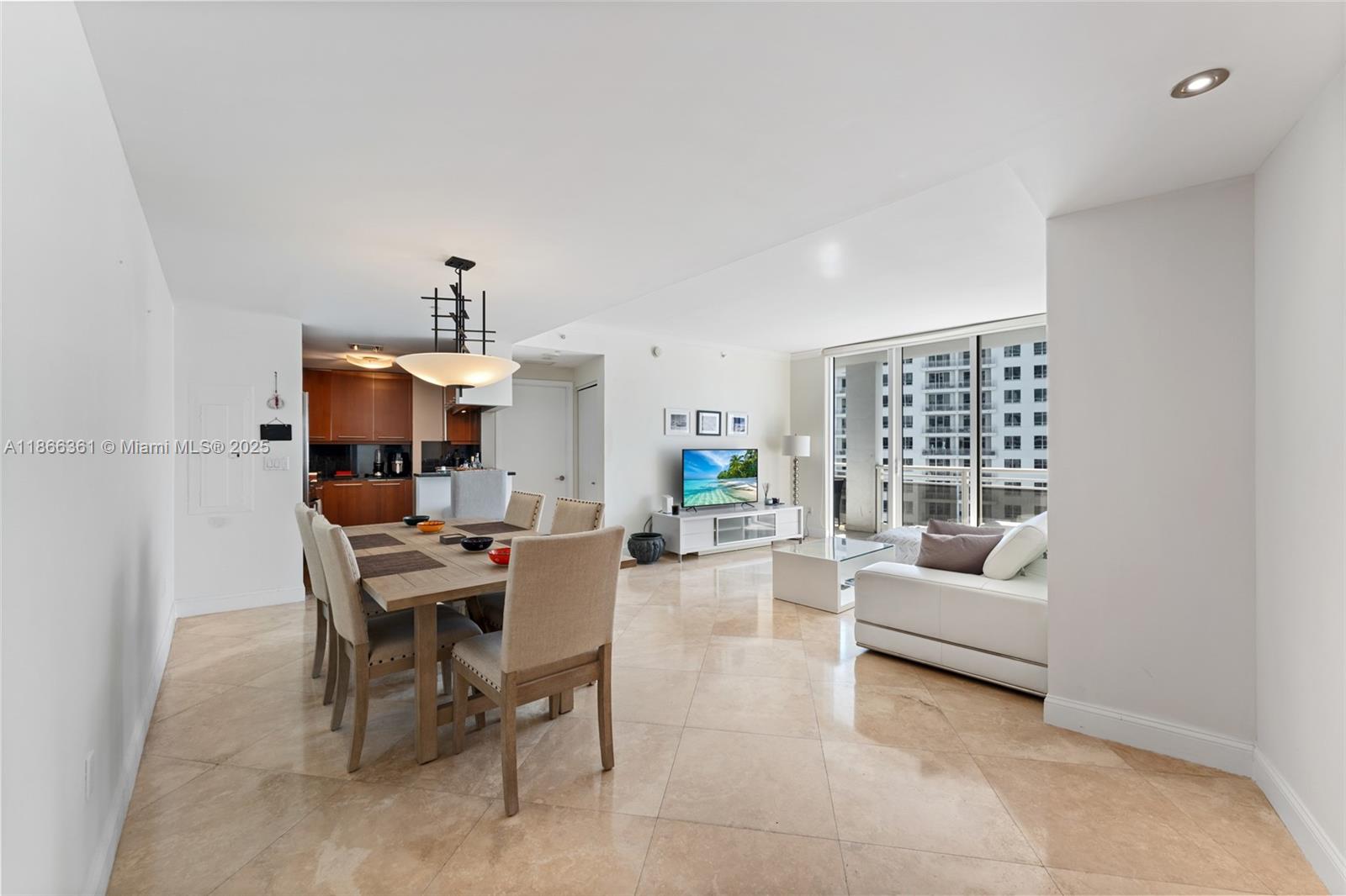 An open-concept living and dining area features tile flooring, a modern kitchen, and balcony access — 901 Brickell Key Blvd # 2801, Miami FL 33131, MIAMI, FL