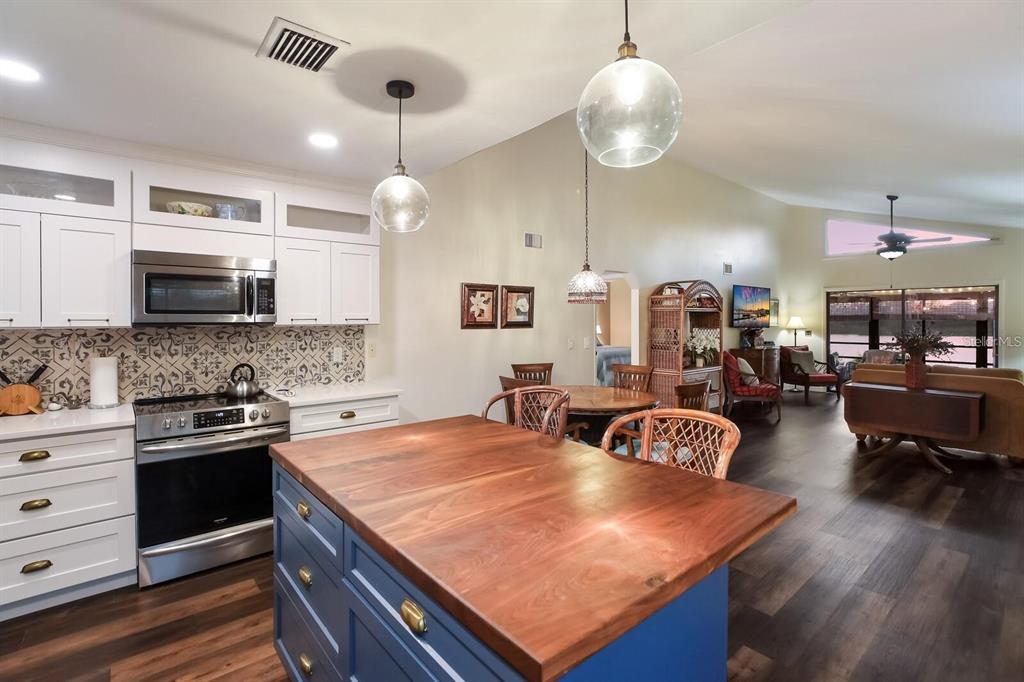 A kitchen with a blue island and wood countertop opens into a living area — 5400 34TH STREET W UNIT 15H, BRADENTON, FL