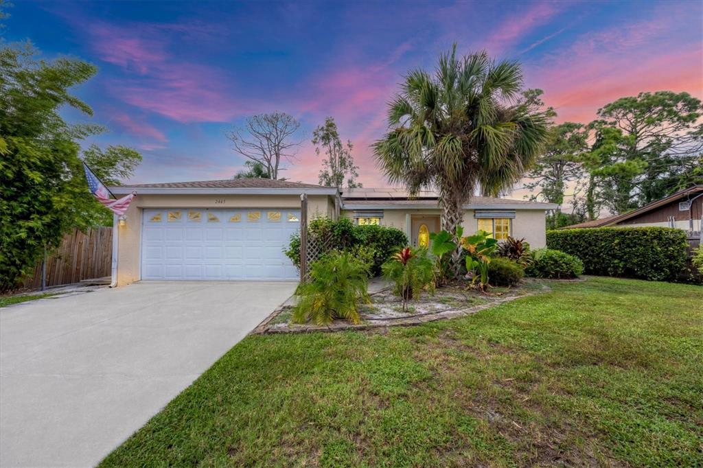 A single-story house with a white garage, a palm tree, and a sunset sky — 2445 APACHE STREET, SARASOTA, FL