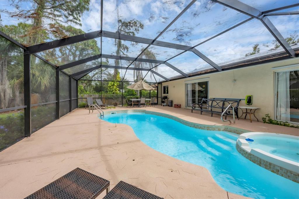 A screened-in patio features a swimming pool, a hot tub, and outdoor furniture — 2445 APACHE STREET, SARASOTA, FL