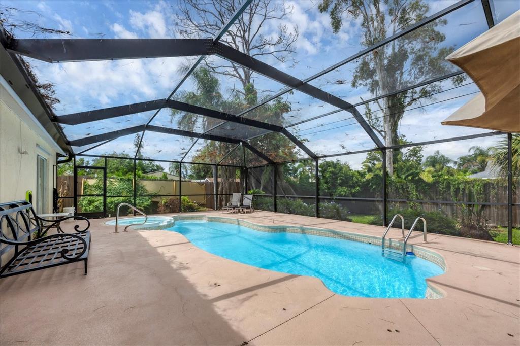 A screened-in patio features a swimming pool, a hot tub, and a metal bench — 2445 APACHE STREET, SARASOTA, FL