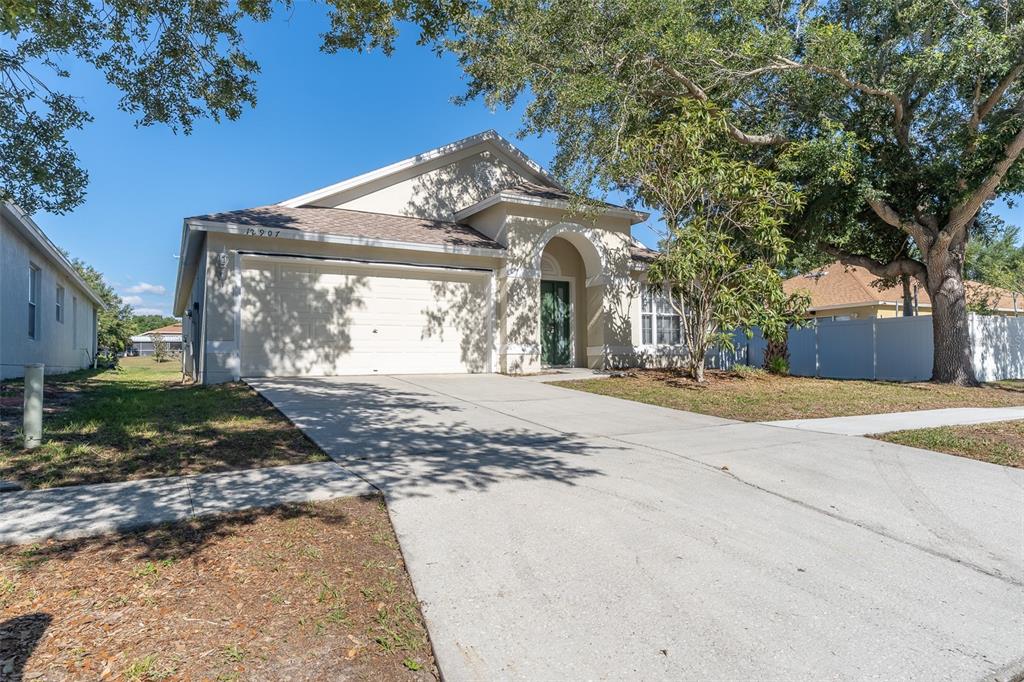 A single-story house with a beige stucco exterior, a two-car garage, and a concrete driveway — 12907 EARLY RUN LANE, RIVERVIEW, FL