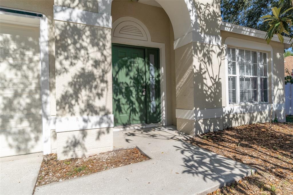 The exterior of a house features a green front door, a concrete walkway, and windows — 12907 EARLY RUN LANE, RIVERVIEW, FL