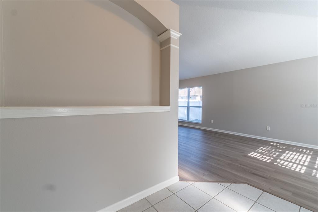 A view from a tiled entryway into a living area with wood-look flooring — 12907 EARLY RUN LANE, RIVERVIEW, FL