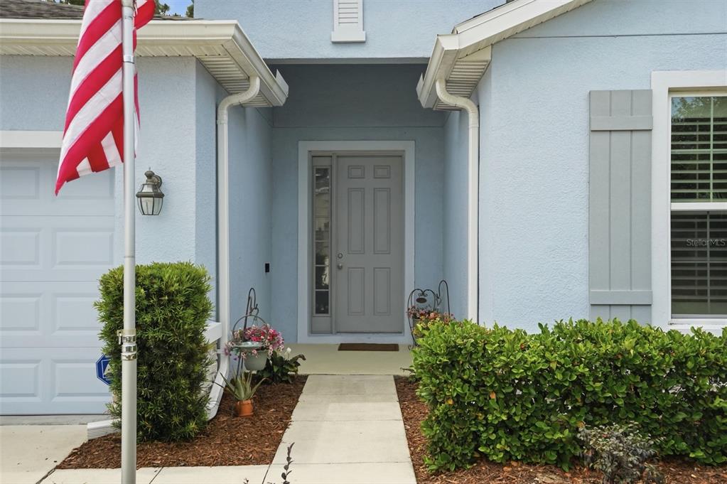 The exterior of a light blue house features a gray front door and a flag pole — 13897 BLYTHEWOOD DRIVE, SPRING HILL, FL