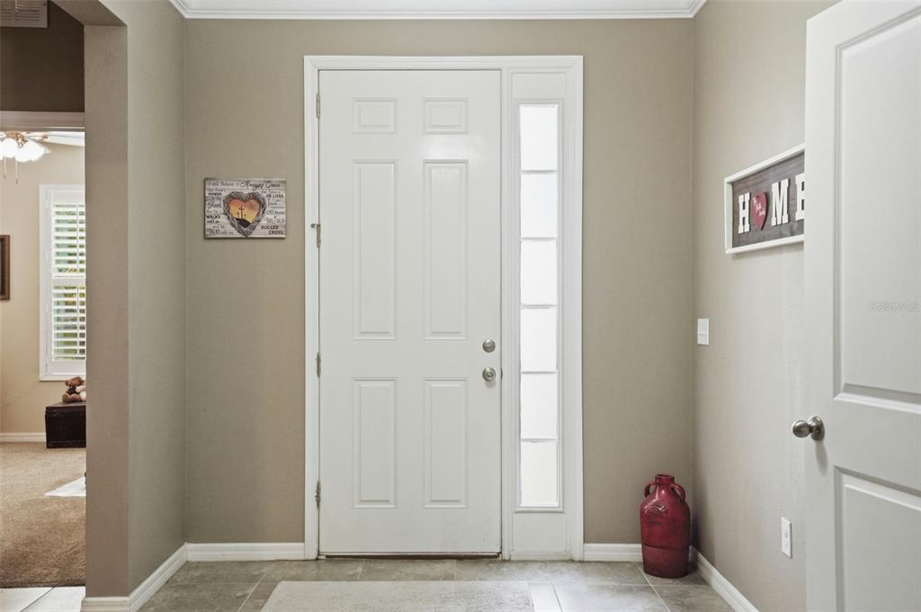 An entryway features a white front door with a sidelight, beige walls, and tile flooring — 13897 BLYTHEWOOD DRIVE, SPRING HILL, FL