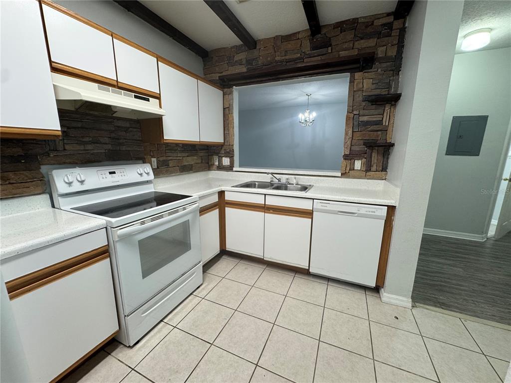 A kitchen features white cabinets, a stone backsplash, a white stove, and a dishwasher — 9621 LAKEDALE WAY UNIT 202, RIVERVIEW, FL
