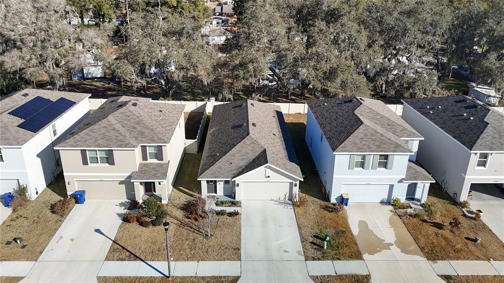 An aerial view shows four suburban houses with driveways and lawns in a residential neighborhood — 37501 SHARKS EYE LANE, ZEPHYRHILLS, FL