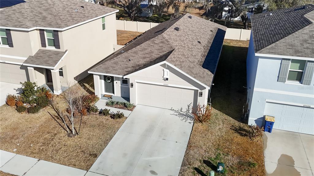 An aerial view shows a single-story house with a shingled roof and a concrete driveway — 37501 SHARKS EYE LANE, ZEPHYRHILLS, FL