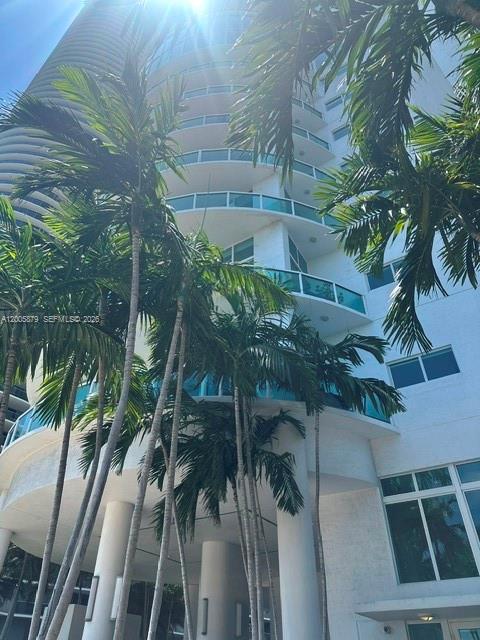 A low-angle view of a white high-rise building exterior framed by palm trees — 1800 N Bayshore Dr # 1506, Miami FL 33132, MIAMI, FL