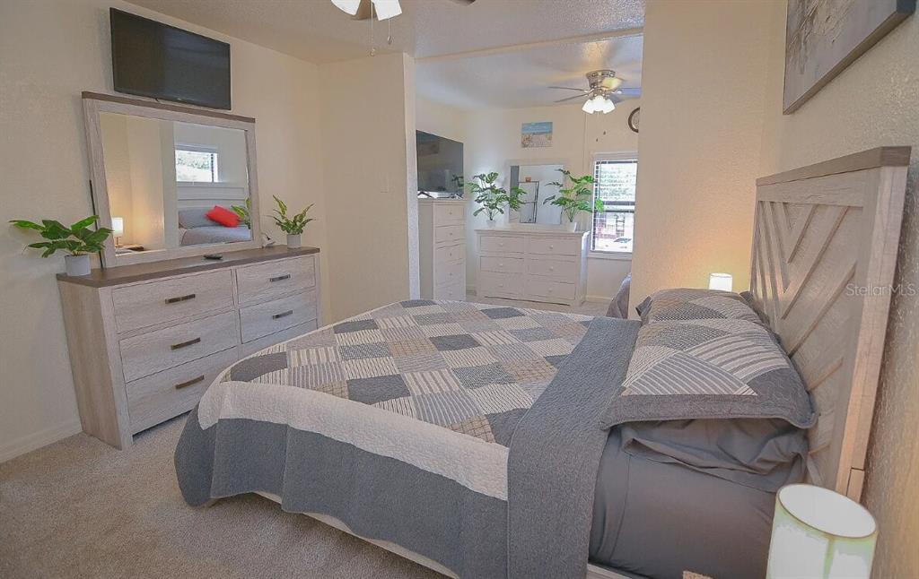 A bedroom features a light wood dresser with a mirror, a bed with a patterned quilt, and a secondary dresser in the background — 358 1ST AVENUE N, LAKE WALES, FL