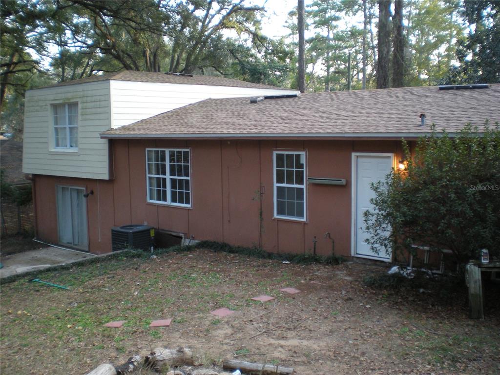 A two-story house with brown siding and a white upper level sits in a yard — 1919 NANTICOKE CIRCLE, TALLAHASSEE, FL