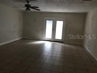 An empty room features tiled flooring, a ceiling fan, and double glass doors — 1919 NANTICOKE CIRCLE, TALLAHASSEE, FL