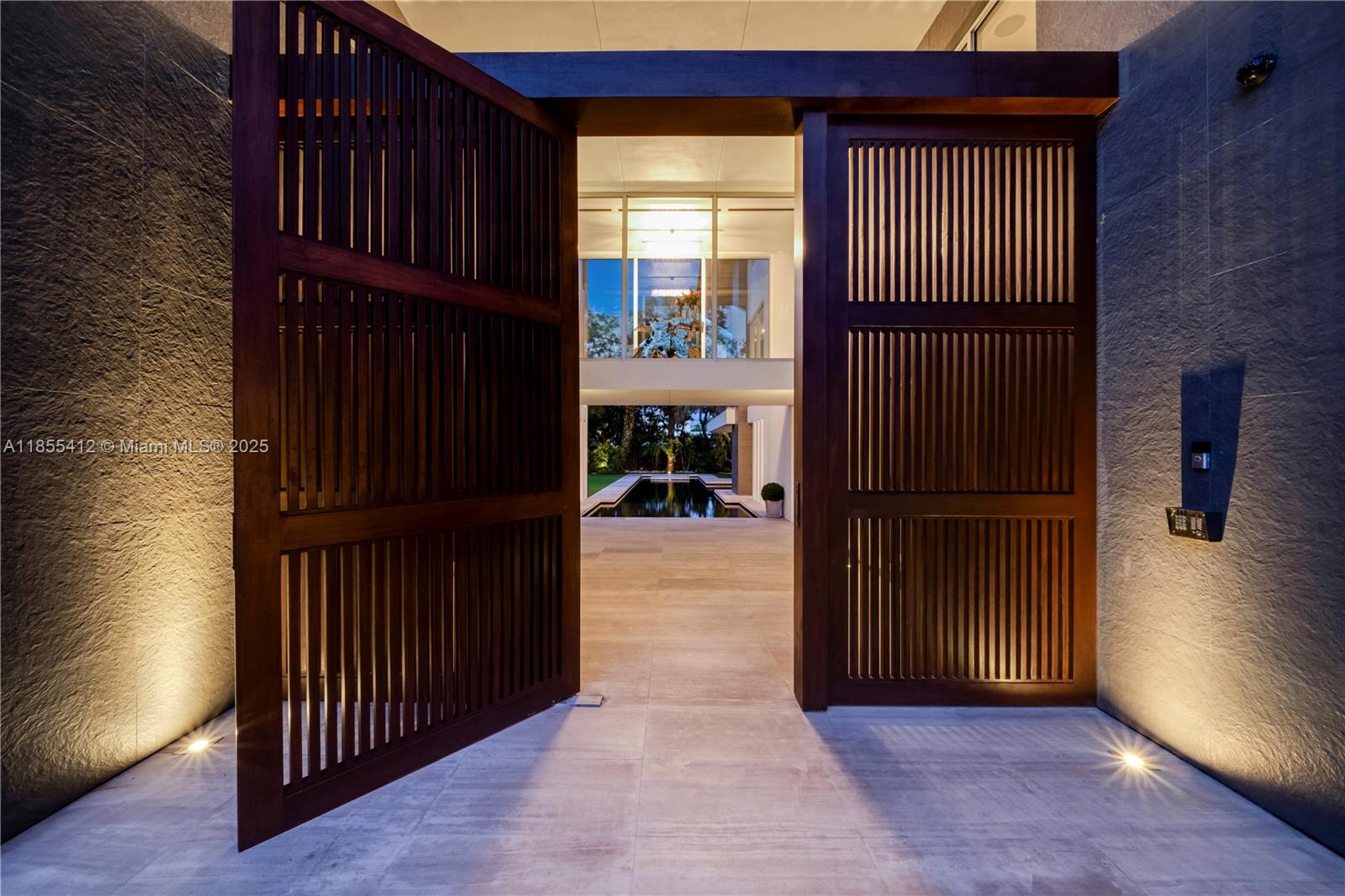 A large wooden gate opens to a courtyard featuring a swimming pool and modern architecture — 545 SABAL PALM, Key Biscayne FL 33149, KEY BISCAYNE, FL