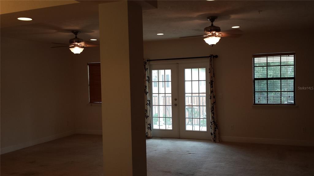A living room features beige carpeting, two ceiling fans, a support column, and French doors — 2602 SW 87TH DRIVE UNIT 201, GAINESVILLE, FL