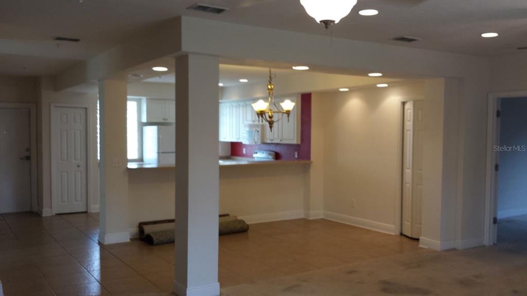 An open-concept kitchen with white cabinets and a breakfast bar overlooks a tiled living area — 2602 SW 87TH DRIVE UNIT 201, GAINESVILLE, FL
