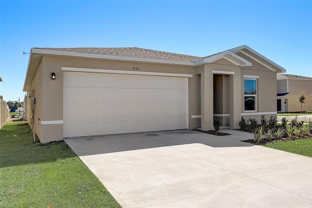 An open-concept kitchen and living area features white cabinets, stainless steel appliances, and wood-look flooring — 1455 HAYWORTH CIRCLE NW, PALM BAY, FL