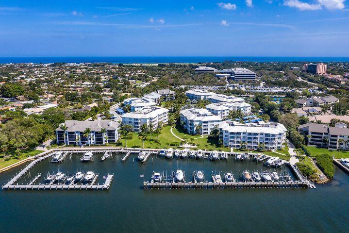 An aerial view shows a waterfront condominium complex with a private boat dock and marina — 834 Bay Colony Drive S, Juno Beach FL 33408, JUNO BEACH, FL