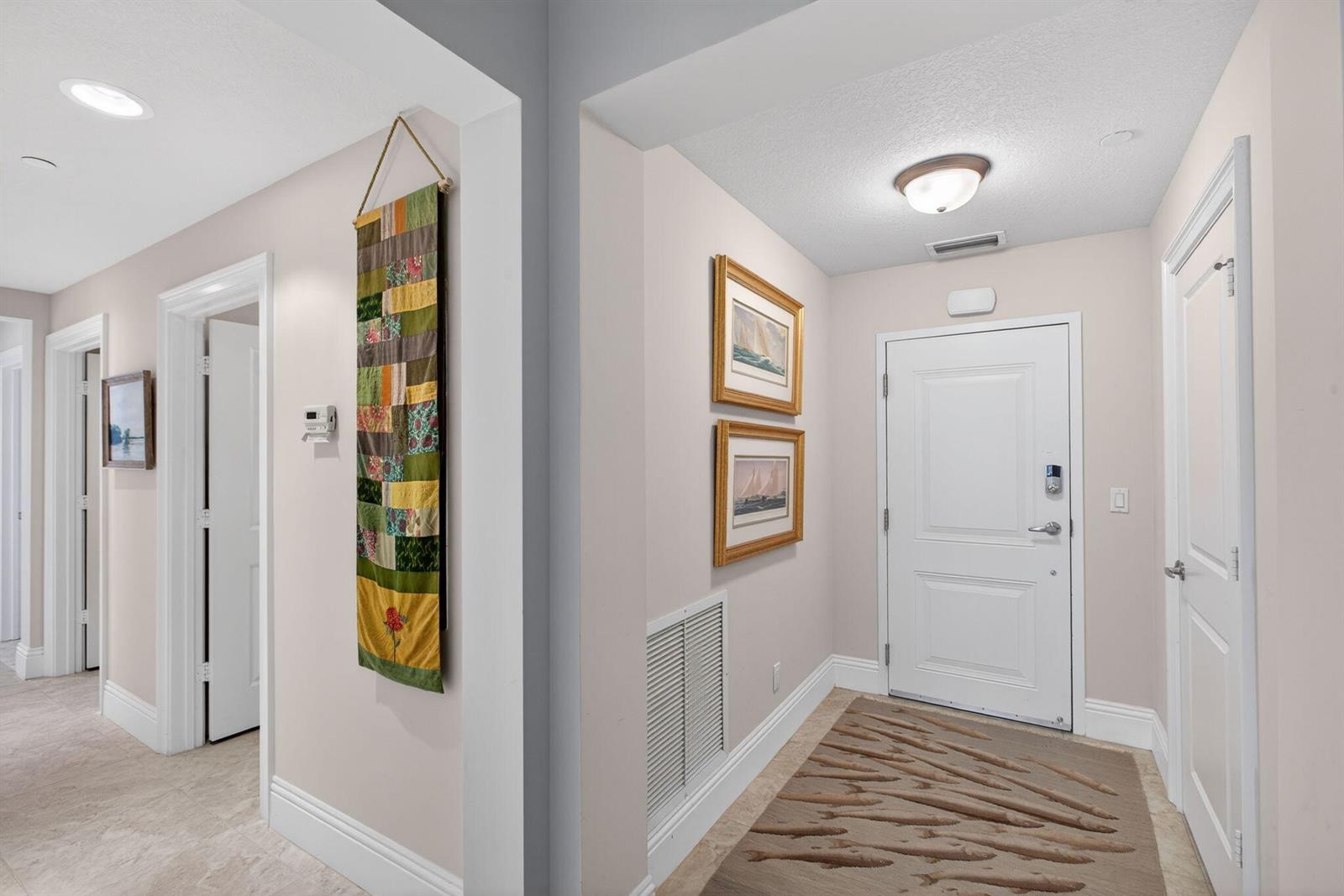An interior entryway features a white door, light-colored walls, tiled floors, and wall-mounted artwork — 834 Bay Colony Drive S, Juno Beach FL 33408, JUNO BEACH, FL