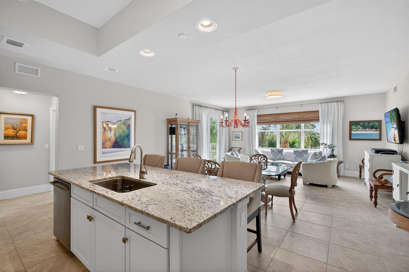A kitchen island with granite countertops overlooks an open-concept living and dining area — 834 Bay Colony Drive S, Juno Beach FL 33408, JUNO BEACH, FL