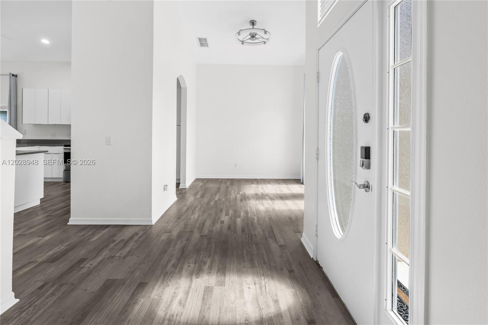 An entryway with wood-look flooring leads to an open living area and a kitchen — 434 Castlemain, Davenport FL 33897, DAVENPORT, FL