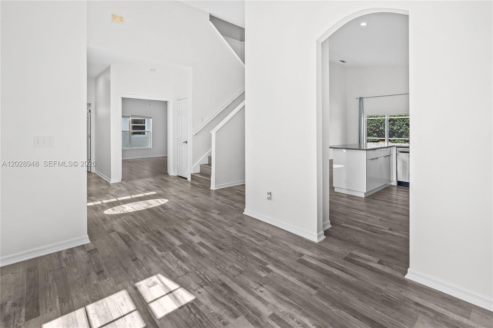 This interior view shows a living area with wood-look flooring, a staircase, and an arched entryway — 434 Castlemain, Davenport FL 33897, DAVENPORT, FL
