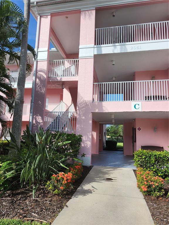 A pink multi-story apartment building exterior features white railings, a staircase, and a walkway — 2061 WILLOW HAMMOCK CIRCLE UNIT 202, PORT CHARLOTTE, FL